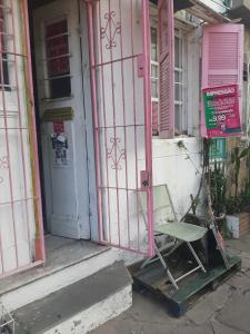 a green chair sitting outside of a pink door at Cytau mesa de trabalho e sofá-cama com ar condicionado, café, wi-fi e água liberados, acesso fácil in Porto Alegre
