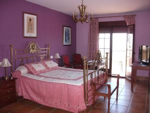 ein Schlafzimmer mit einem Bett und einer lila Wand in der Unterkunft Hotel Los Rebites in Huétor Vega