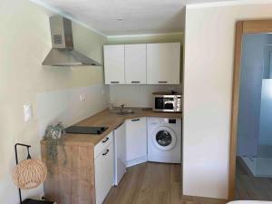 a kitchen with white cabinets and a washer and dryer at A Casetta Di Oletta in Oletta