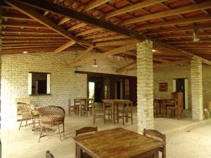 a patio with tables and chairs and a brick wall at Jungle House in São Miguel do Gostoso