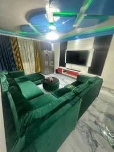 a living room with a green couch and a tv at Premier Elegant Apartments in Harare