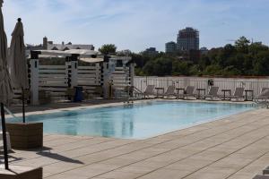 ジャージー・シティーにあるChique Loft 15 Min from NYC with City View & Poolの建物内のスイミングプール(椅子、パラソル付)