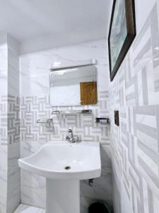 a white bathroom with a sink and a mirror at GrandTaj in Murree