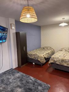 リマにあるCuzco Lodgementのベッド2台、テレビ、シャンデリアが備わる客室です。