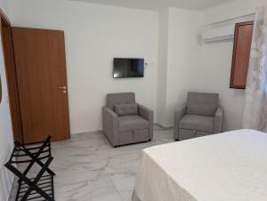 a bedroom with two chairs and a tv on the wall at Infinity House Catania in Catania
