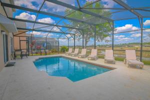 einen Pool mit Liegestühlen und einem Wintergarten in der Unterkunft The Andalusian Escape Near Disney in Davenport