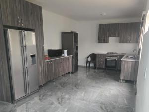 a kitchen with wooden cabinets and a stainless steel refrigerator at Arch Ocean View in Chintsa