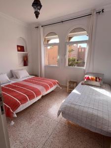 a bedroom with two beds and two windows at Villa avec vues sur dunes, montagnes et océan! Accès plage direct! Proche SIDI BOULFDAIL et AGLOU in Tamellalt