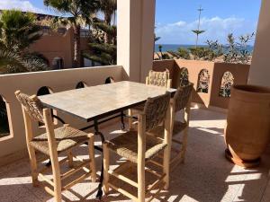 a table and chairs on a balcony with a view of the ocean at Villa avec vues sur dunes, montagnes et océan! Accès plage direct! Proche SIDI BOULFDAIL et AGLOU in Tamellalt