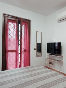 Un dormitorio con una cama y un televisor y una ventana. en Le Terrazze Ciampino, en Ciampino