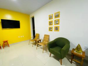 a living room with a green chair and yellow walls at Casa Miriti Hostel in Belém