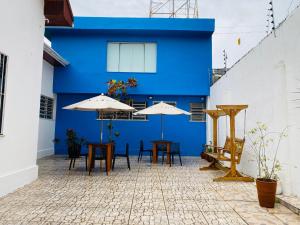 贝伦Casa Miriti Hostel - a 200m da Basílica de Nazaré的庭院里带桌子和遮阳伞的蓝色建筑