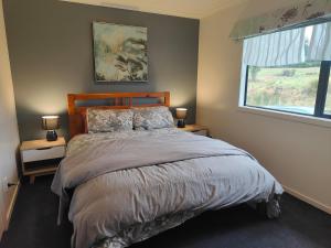 1 dormitorio con 1 cama con 2 mesitas de noche y una ventana en Ohakune Peak Retreat Unit 2, en Ohakune