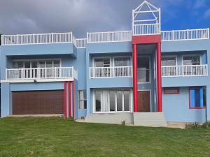 a blue building with a red door and a garage at Arch Ocean View in Chintsa