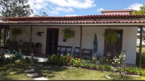 a small house with chairs and flowers in the yard at Recanto de Lila in Ibicoara