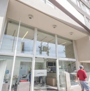 a man walking in front of a building with large windows at Full Equipado a pasos Metro Ecuador in Santiago