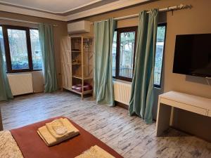 a bedroom with green curtains and a tv on a wall at Keyfe Kadir Garden Butik Otel in Orhangazi