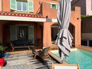 a patio with a large umbrella and a pool at Villa avec piscine privative et vue imprenable sur le golf de Saint-Florent à 300 m de la plage in Saint-Florent