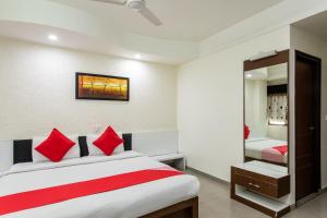 博帕尔Hotel O Mohit Regency的一间卧室配有一张带红色枕头和镜子的床
