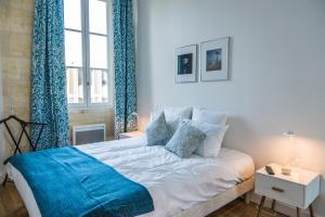 a bedroom with a large white bed with blue curtains at Bordeaux Traditions in Bordeaux