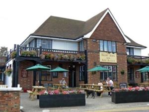 a building with tables and umbrellas in front of it at Lovely Chalet 15, Seadell Park in Hemsby