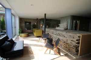 a living room with chairs and a stone wall at Hotel Apartamentos Casas da Fortaleza in Lugo