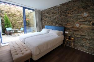a bedroom with a large bed and a brick wall at Hotel Apartamentos Casas da Fortaleza in Lugo