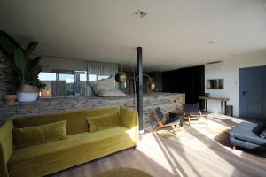 a living room with a yellow couch and chairs at Hotel Apartamentos Casas da Fortaleza in Lugo