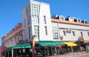 een hoog wit gebouw aan een stadsstraat bij Studio apartman Laura in Vinkovci