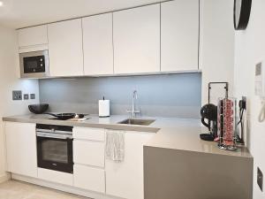 a kitchen with white cabinets and a sink at 18th Floor Luxury Studio in Gibraltar