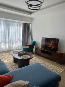 a living room with a blue couch and a flat screen tv at Homely and Spacious 2 bed at Marina Bay in Nairobi