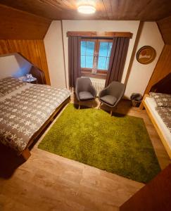a bedroom with a bed and two chairs and a green rug at Chata Alaska in Jáchymov +25 photos