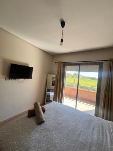 a bedroom with a bed with a television and a window at Comme a la maison Prestigia Golf acces piscine in Marrakesh