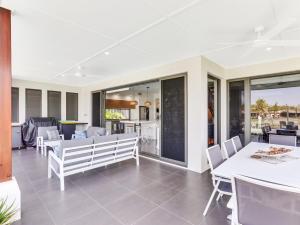 a patio with white chairs and tables and windows at WATERFRONT HOME BORDERING MOOLOOLABA in Buddina