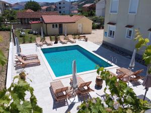 a pool with chairs and umbrellas next to a building at Apartmani Ćućić in Lopar