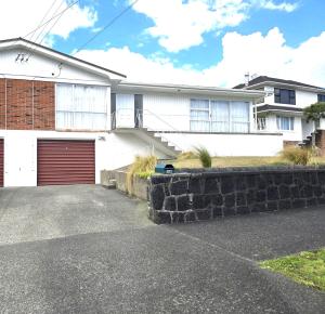 a white house with a red garage at Sunny Villa Guest House in Auckland