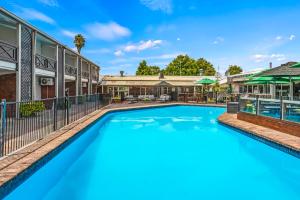a swimming pool in front of a building with a house at Poenamo Hotel in Auckland