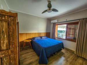 a bedroom with a blue bed and a window at Casa Pé na Areia in Balneario Barra do Sul