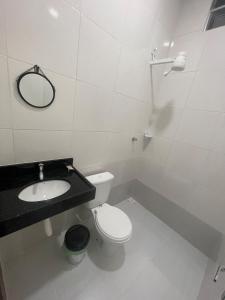 Un baño con inodoro, lavabo y espejo. en Great House1, en Manaus