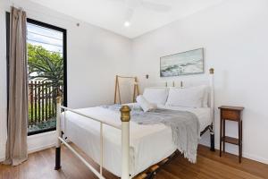 Un dormitorio blanco con una cama y una ventana. en Oceanic-Pet Friendly Townhouse 8min to Mooloolaba, en Parrearra