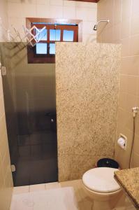 uma casa de banho com um WC e uma porta de duche em vidro. em Sueds Cabralia em Santa Cruz Cabrália