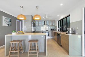 una cucina con una grande isola con due sgabelli da bar di YALLA24-Luxury Resort Style Home a Mooloolaba
