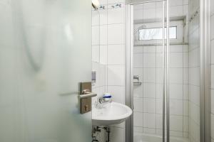 a white bathroom with a sink and a shower at Hotel Mythos in Rust