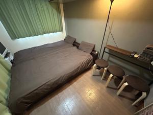 ein Schlafzimmer mit einem Bett mit zwei Stühlen und einer Lampe in der Unterkunft Guest House Yakuin INN in Fukuoka