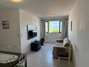 un salon avec un canapé, une table et une télévision dans l'établissement Apartamento Vista Mar, à Maceió