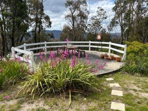 a white fence with a table and some flowers at Mountain Tranquility in Mount Tomah