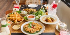ein Tisch voller Teller mit Essen und Pommes frites in der Unterkunft Ayla Chalet in Phrae