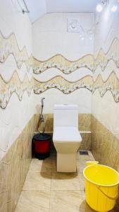 a bathroom with a toilet and a yellow bucket at mountain lake view private pool villa -Wayanad in Meppādi