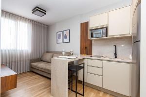 a kitchen with white cabinets and a couch in a room at Apto confortável Centro/Batel in Curitiba