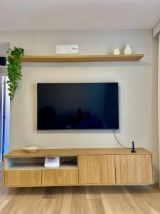a flat screen tv sitting on top of a wooden entertainment center at Praia de Piratininga Apartamento Vista Para o Mar in Niterói